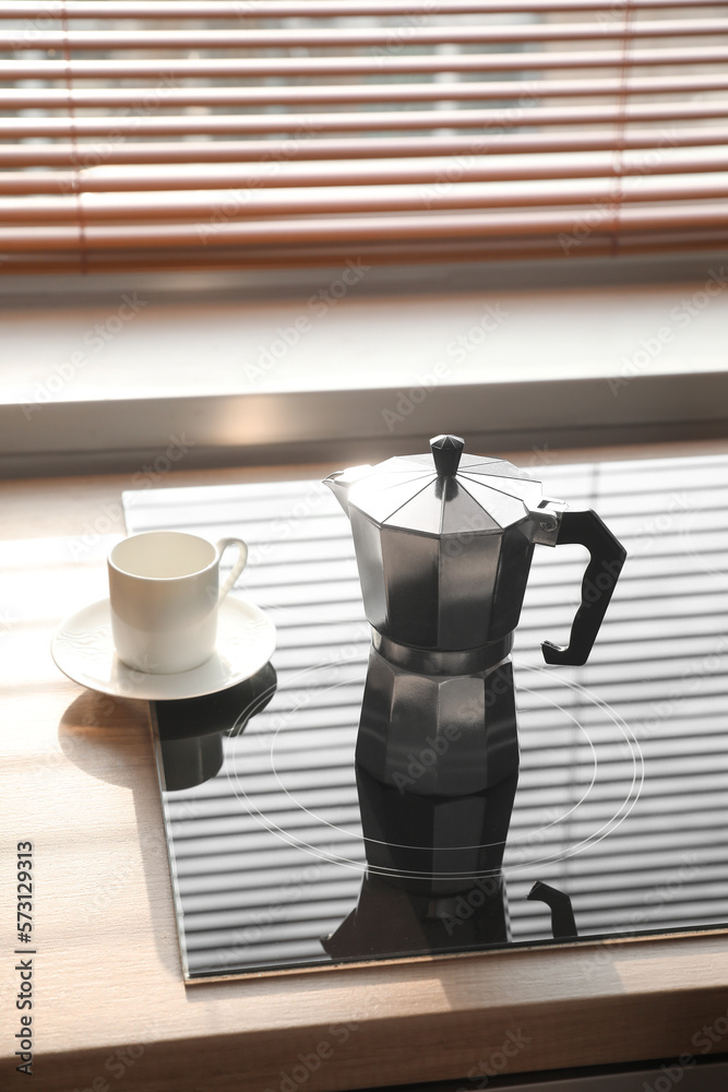 Geyser coffee maker on electric stove in kitchen near window