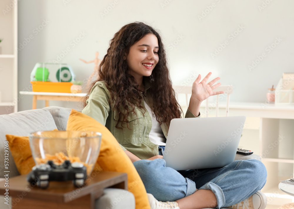 Teenage girl using laptop on sofa at home