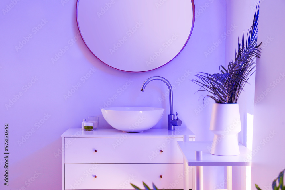 Interior of stylish bathroom with ceramic sink, mirror and neon lighting