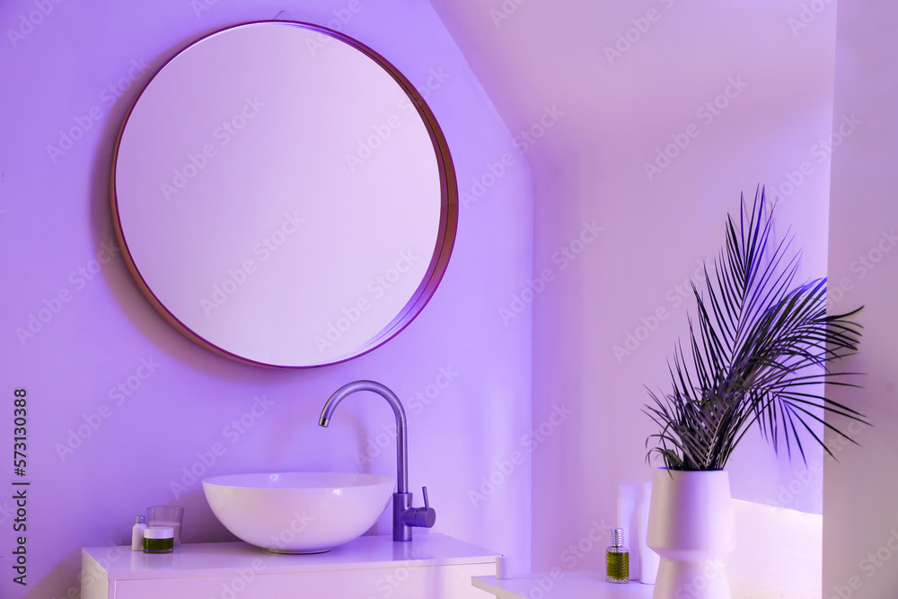 Interior of stylish bathroom with ceramic sink, mirror and neon lighting