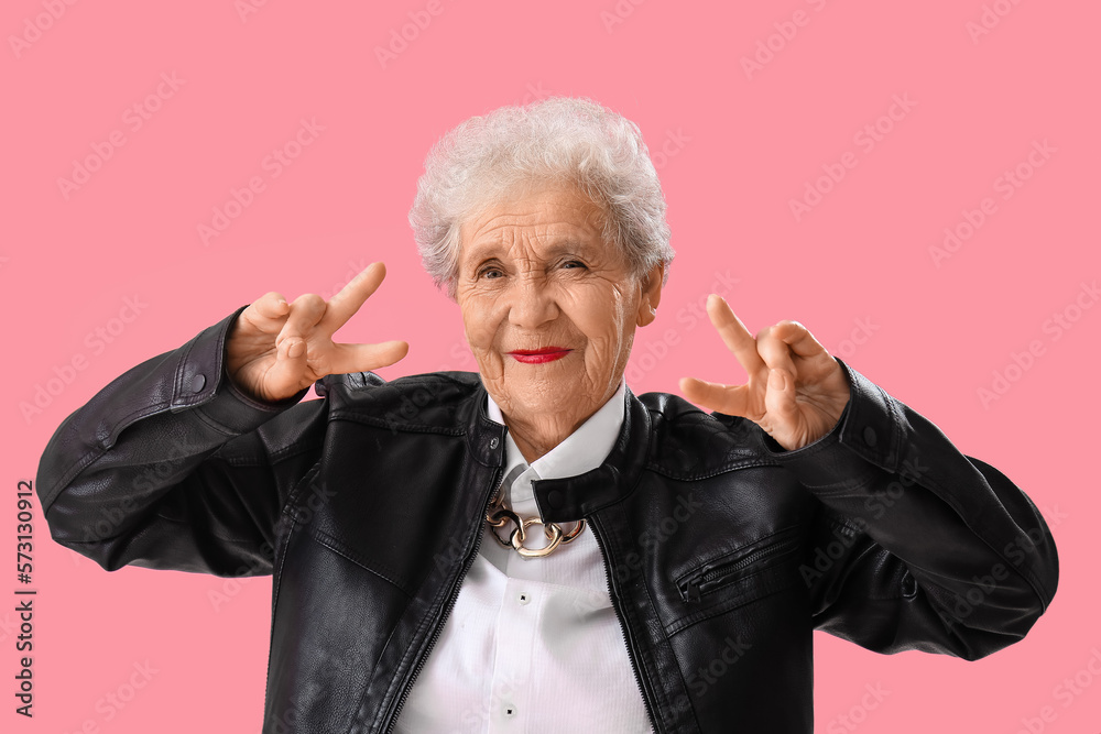 Senior woman in leather jacket showing victory gesture background