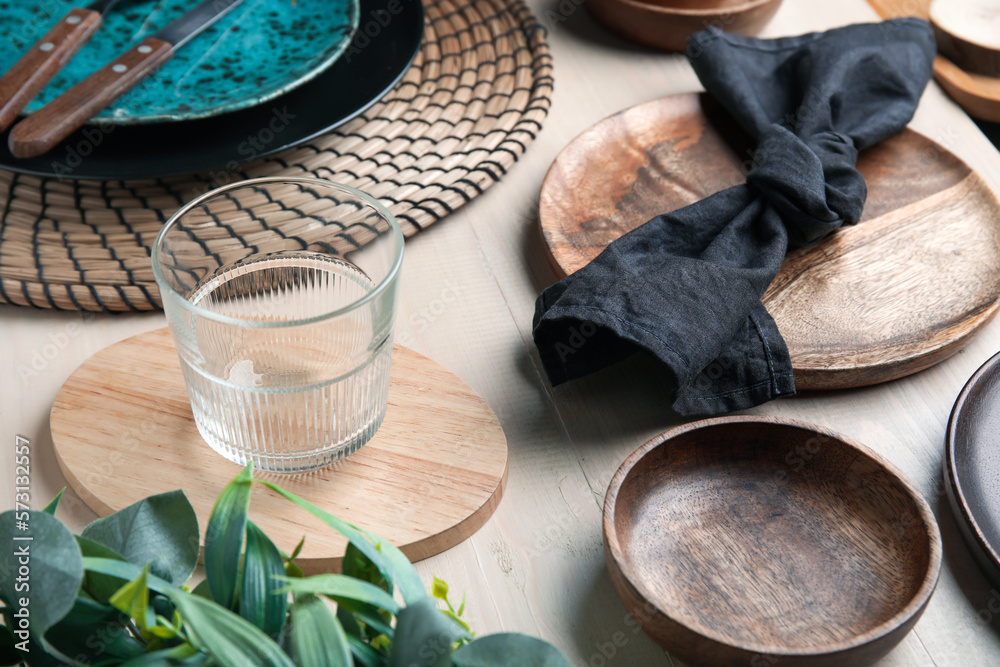 Stylish table setting with glass of water and napkin on white wooden background