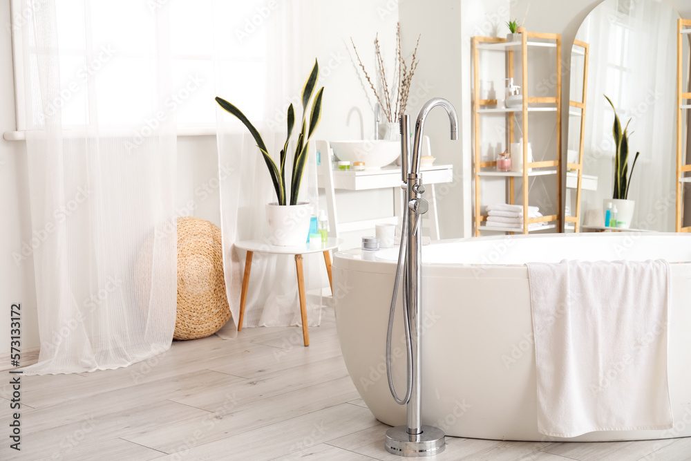 Interior of bathroom with bathtub, mirror and shelving unit