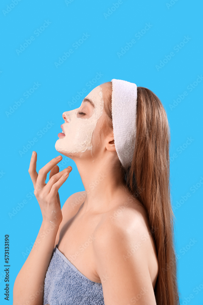 Young woman with applied turmeric mask on blue background