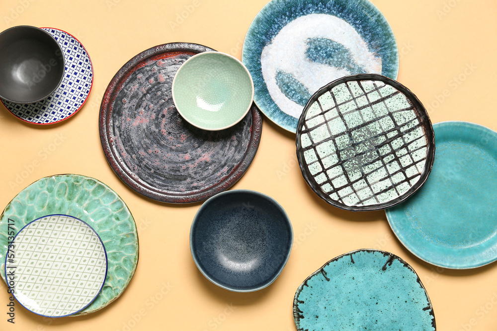 Set of different ceramic plates on color background