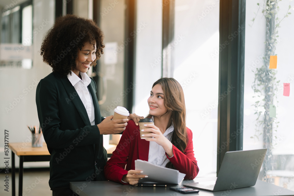 Happy two young business woman holding coffee cup in coworking office.