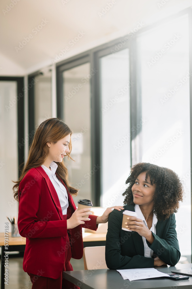 Happy two young business woman holding coffee cup in coworking office.