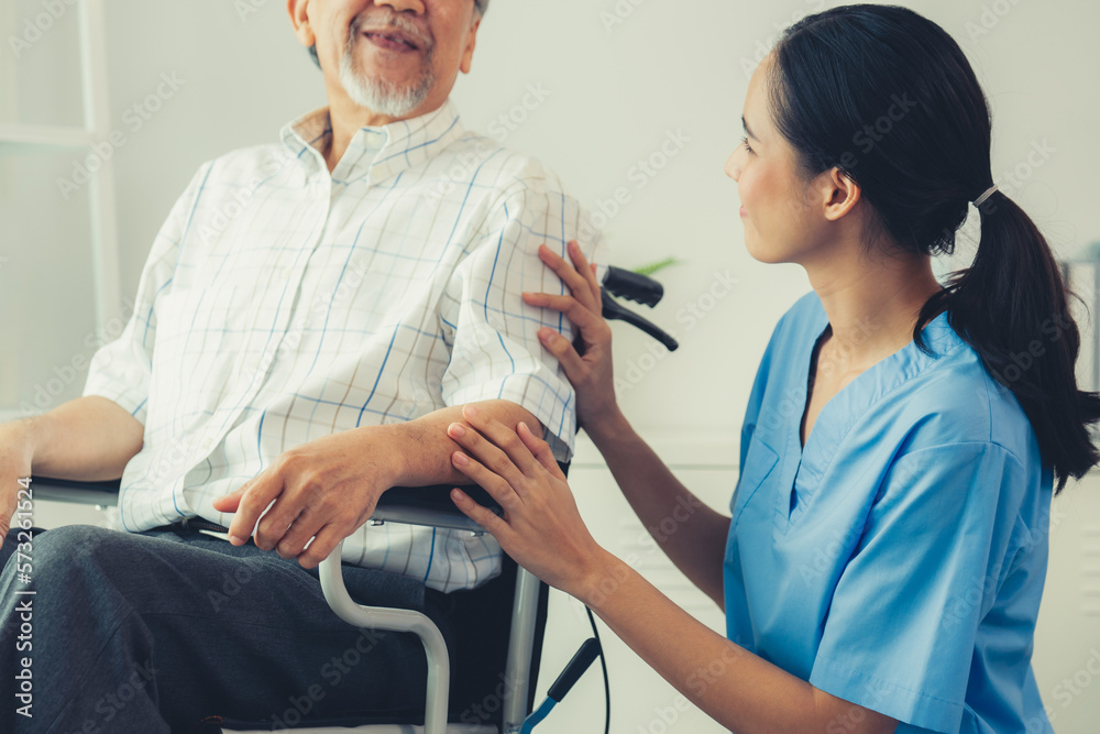 Happy positive asian nurse giving support and touching contented senior man with love. Nursing home 