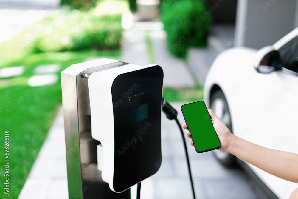 Mockup phone with green screen display energy status of electric vehicle connected to charging stati