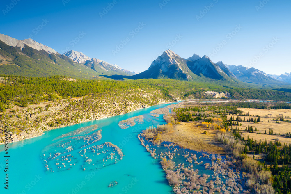 A drone view of the river in the mountains valley. An aerial view of an autumn forest. Winding river