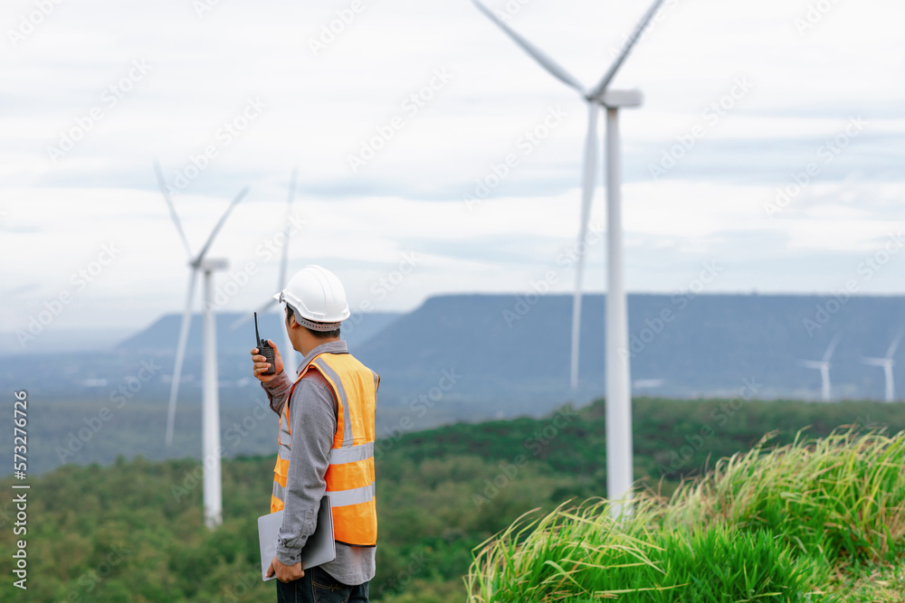 Engineer working on a wind farm atop a hill or mountain in the rural. Progressive ideal for the futu