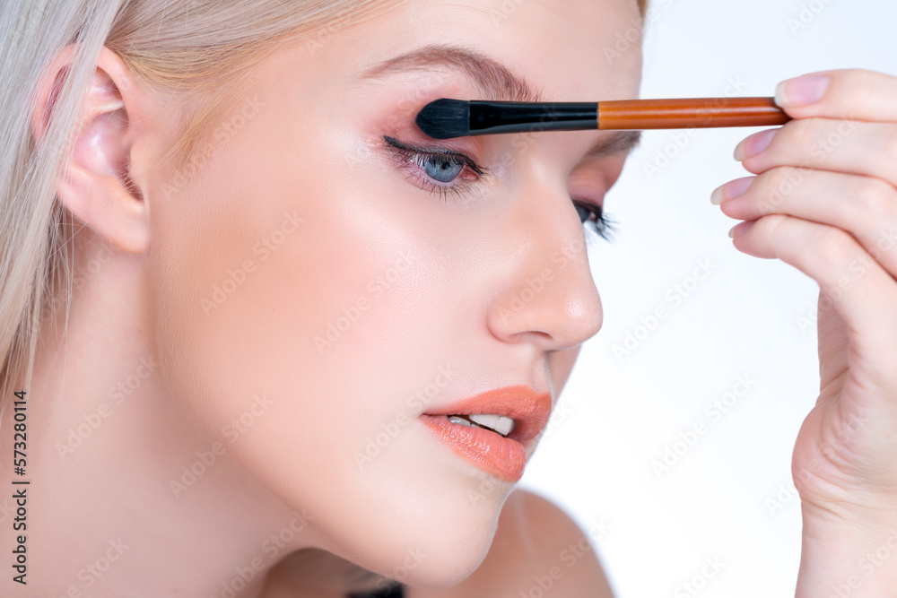 Closeup beautiful personable girl with flawless applying eye shadow makeup with eyeliner brush. Cosm