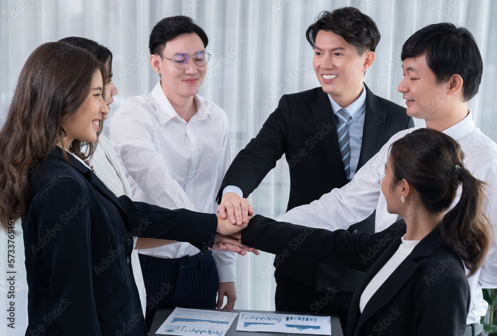 Closeup business team of suit-clad businessmen and women join hand stack together and form circle. C