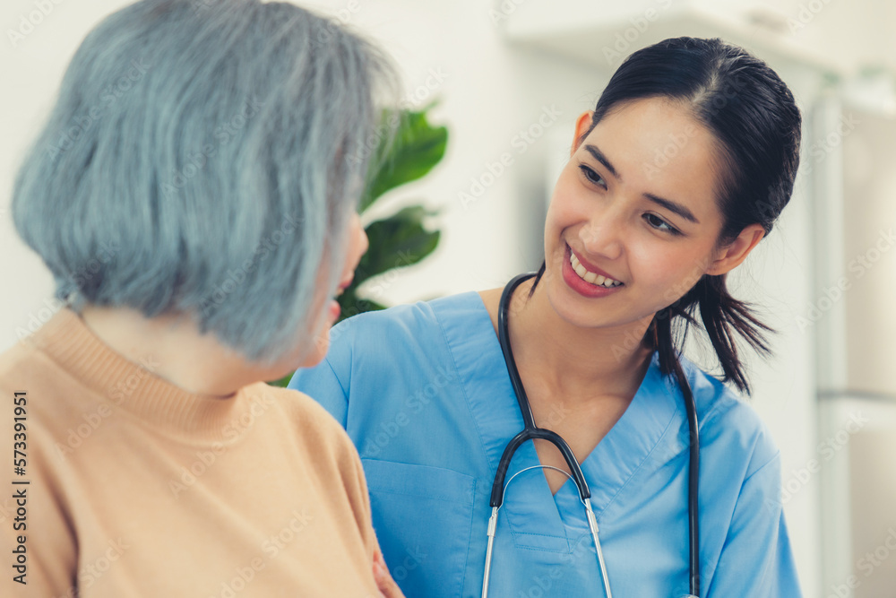 A caregiver rest her hands on the shoulders of a contented senior patient while she sitting on the s