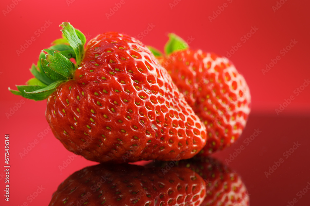 Strawberries on a red background. Two Fresh ripe strawberries on red, macro shot of fresh juicy berr