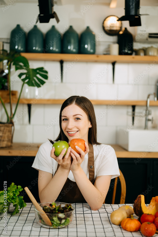 beautiful adult woman with bell peppers looking at camera while making salad at kitche. healthy food