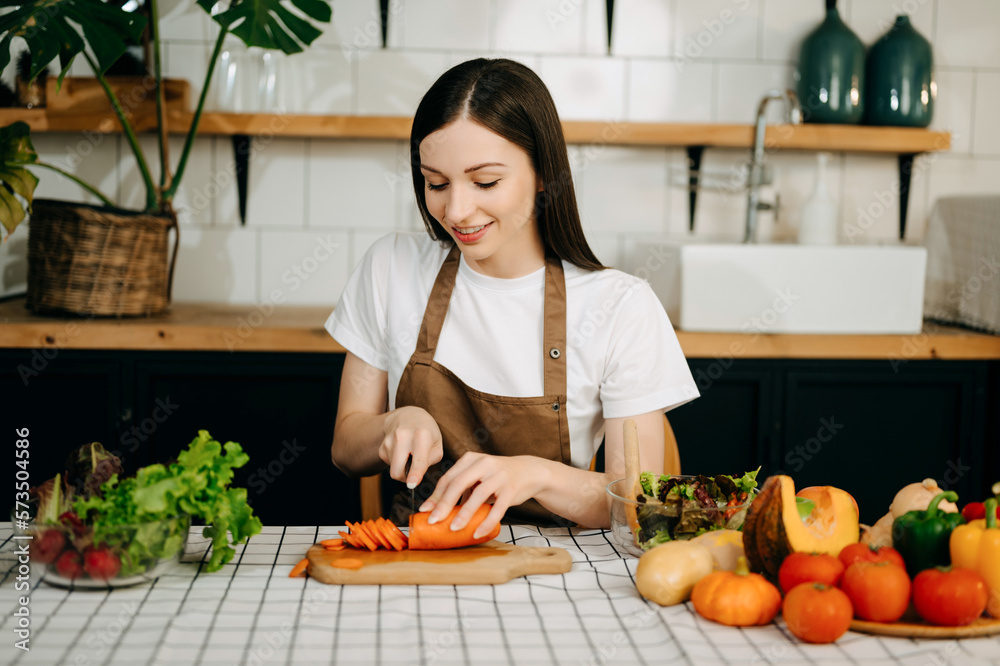 beautiful adult woman while making salad at open kitchen. healthy food concept..