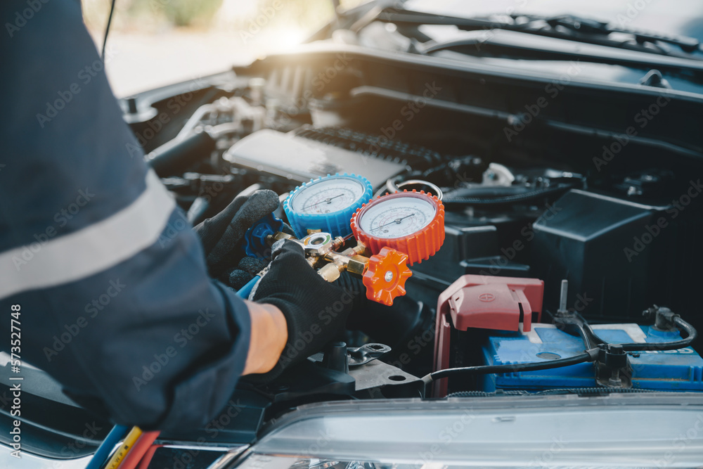 Close up hand of auto mechanic using measuring manifold gauge check the refrigerant and filling car 