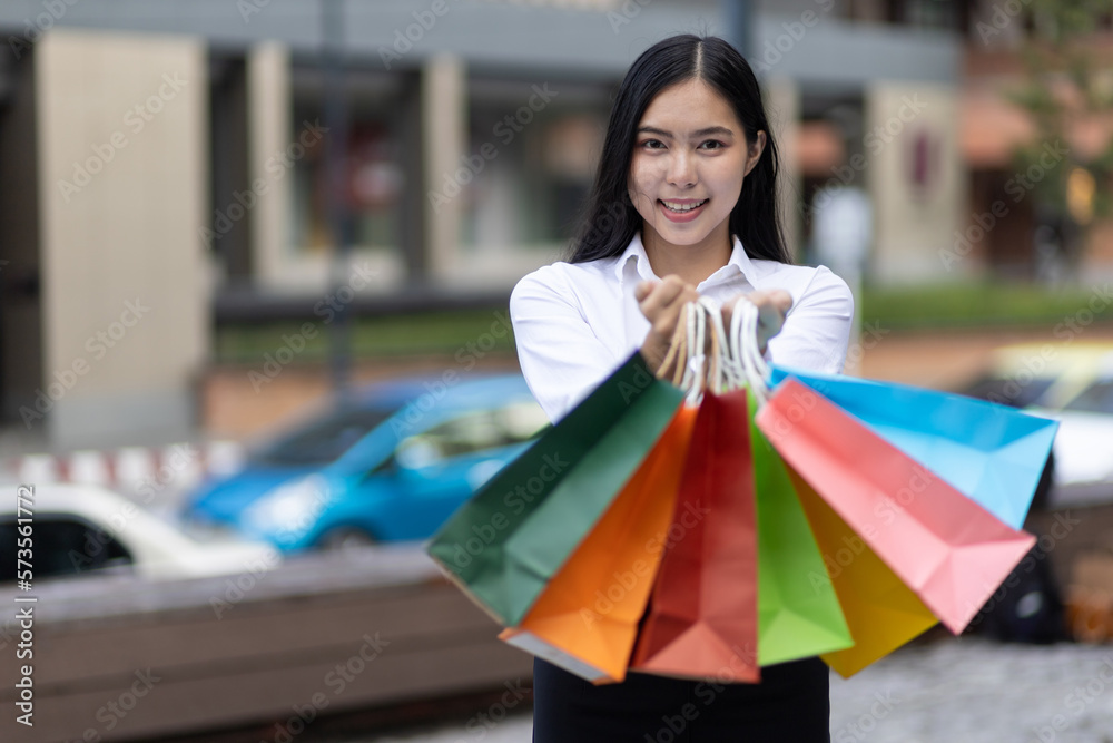 Cheerful and attractive young Asian woman carrying shopping bags. Female tourist carrying shopping b