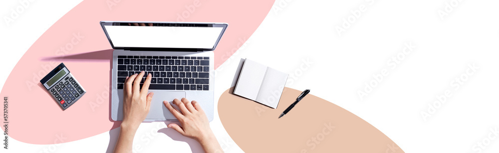 Person using a laptop computer with a notebook and a calculator