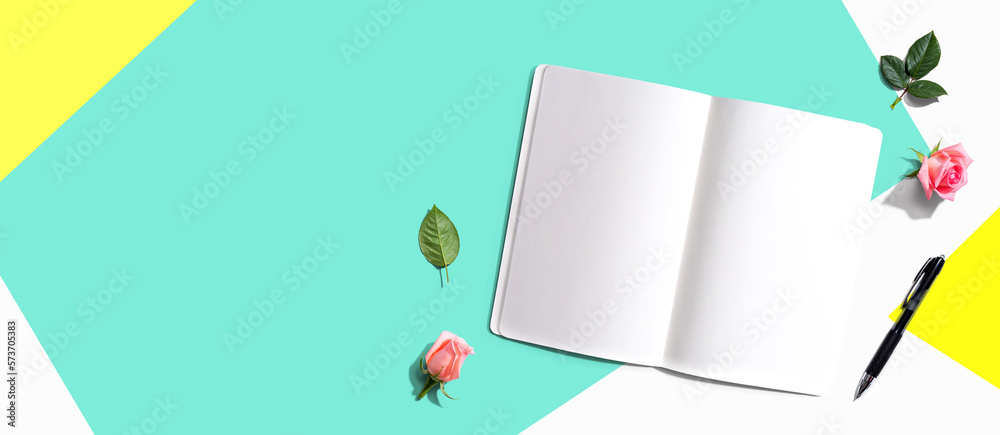 Open notebook or diary with a pen from above with rose buds- flat lay