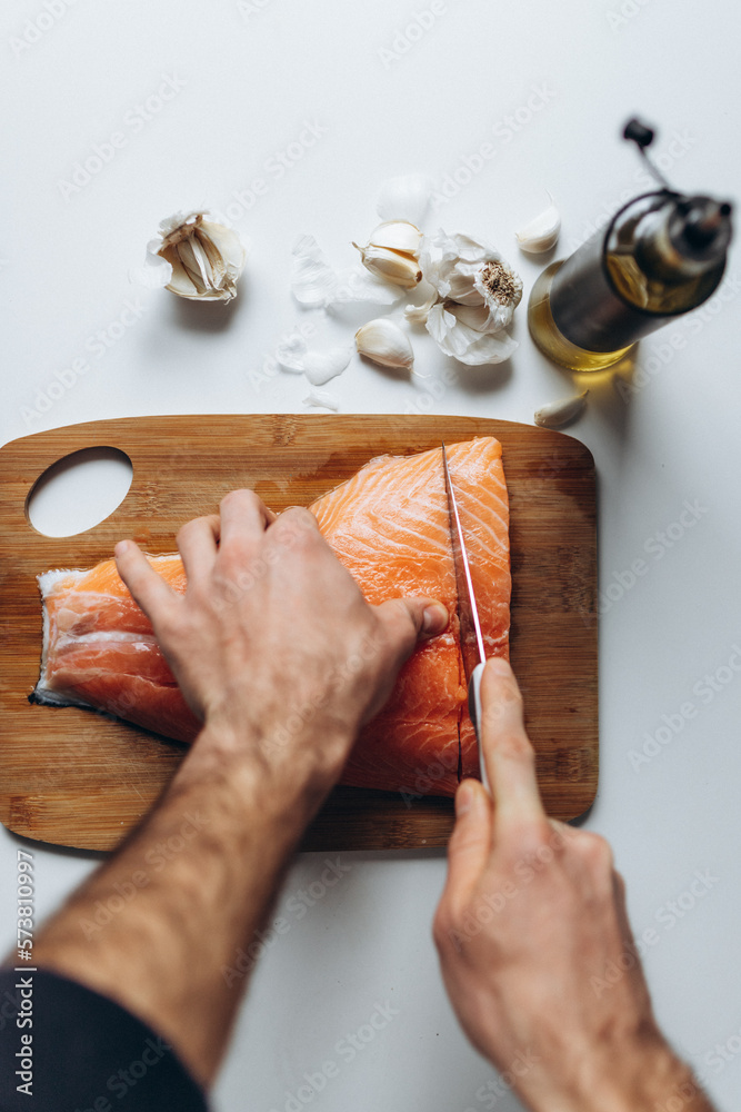 A man cutting a raw salmon into pieces