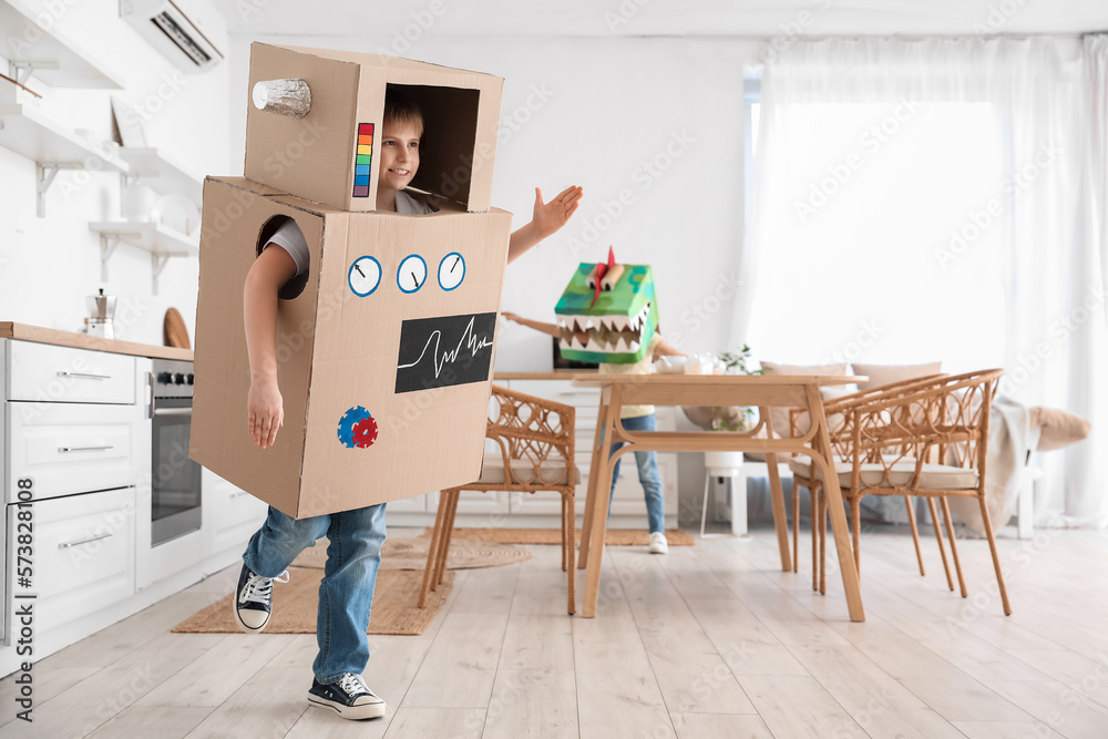 Little boy in cardboard robot costume playing at home