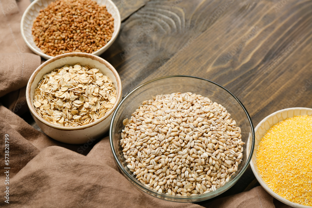 Bowls with cereals on wooden background, closeup