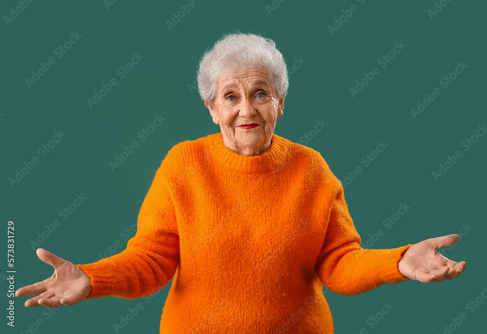 Senior woman in orange sweater on green background