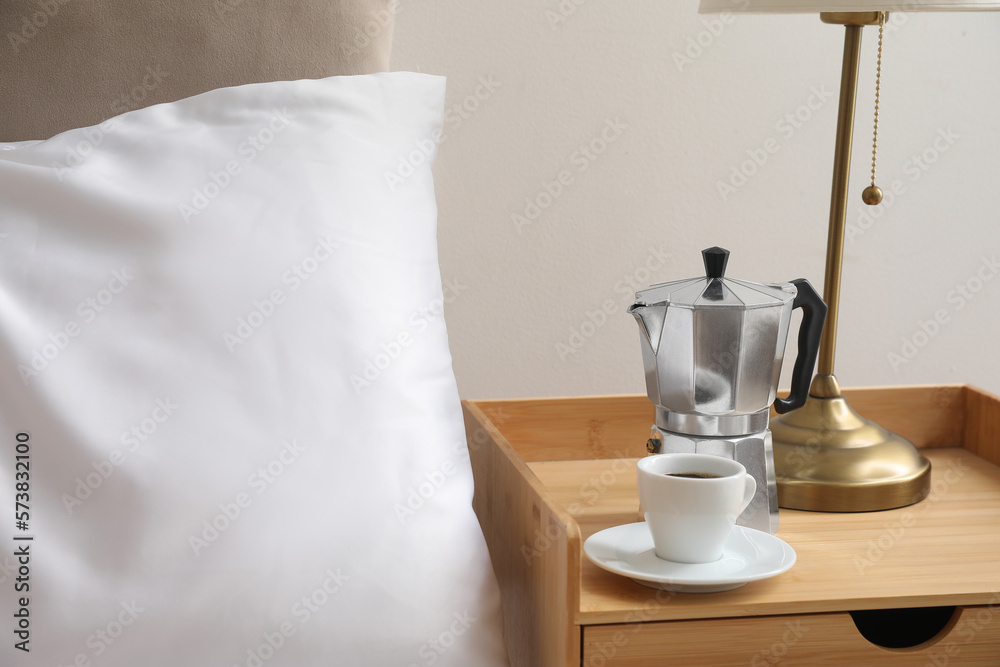 Geyser coffee maker and cup of espresso on nightstand near bed