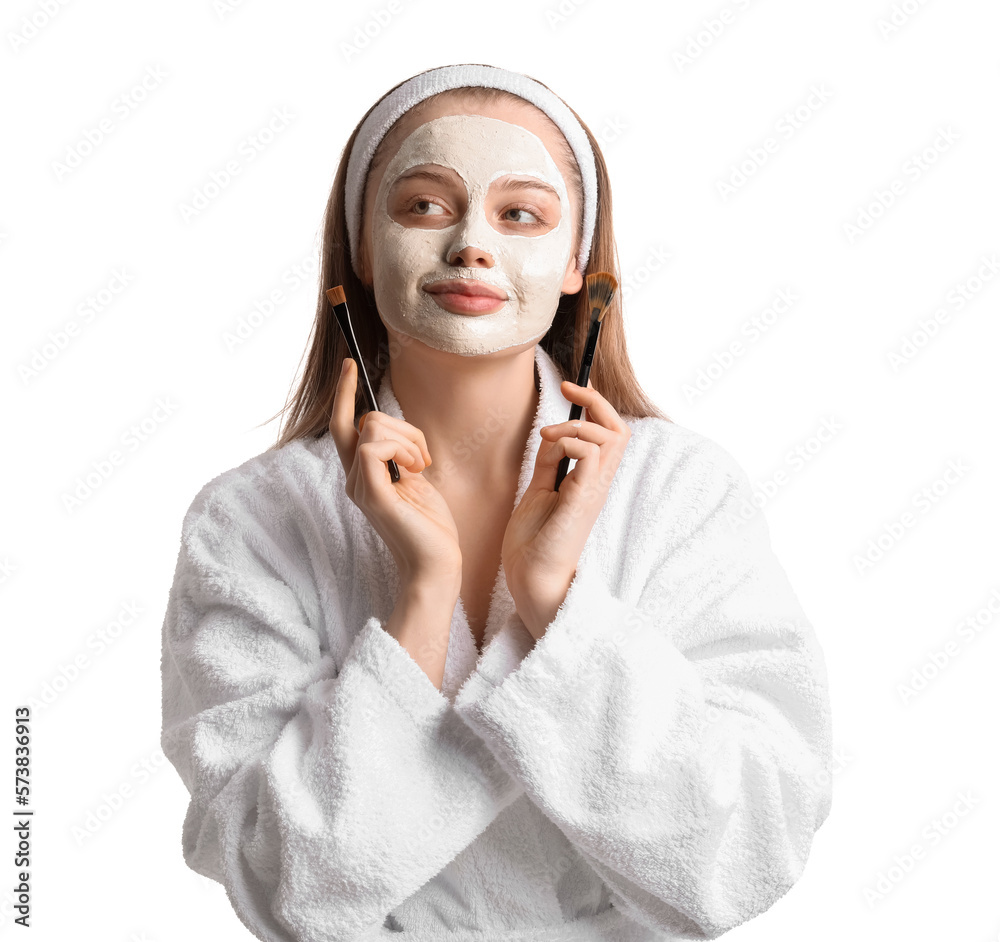 Young woman with applied turmeric mask and brushes on white background