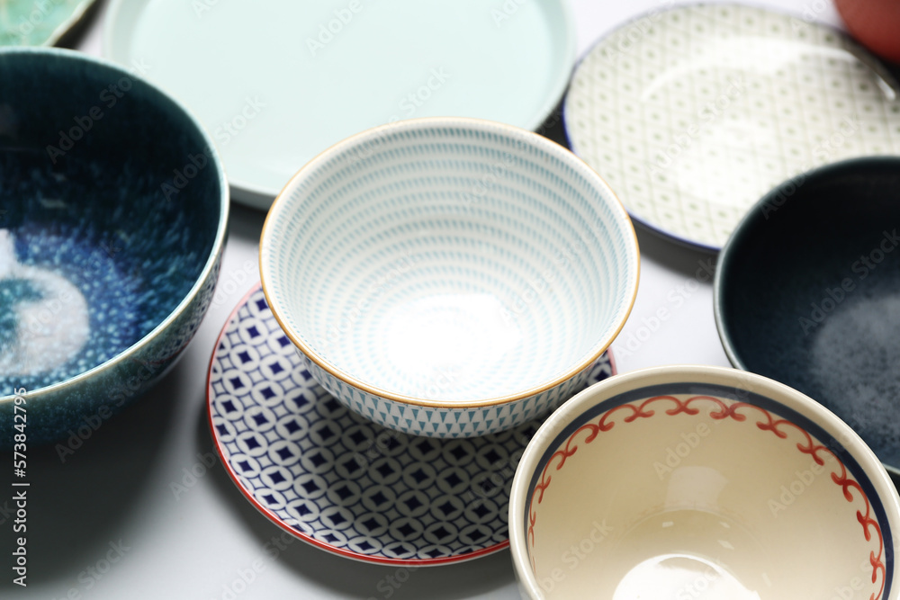 Clean ceramic plates and bowls on white background