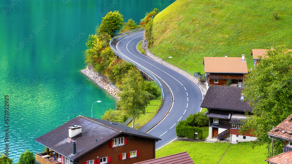 Lungern, canton of Obwalden, Switzerland. A view of rural homes in a green meadow. A lake in a mount