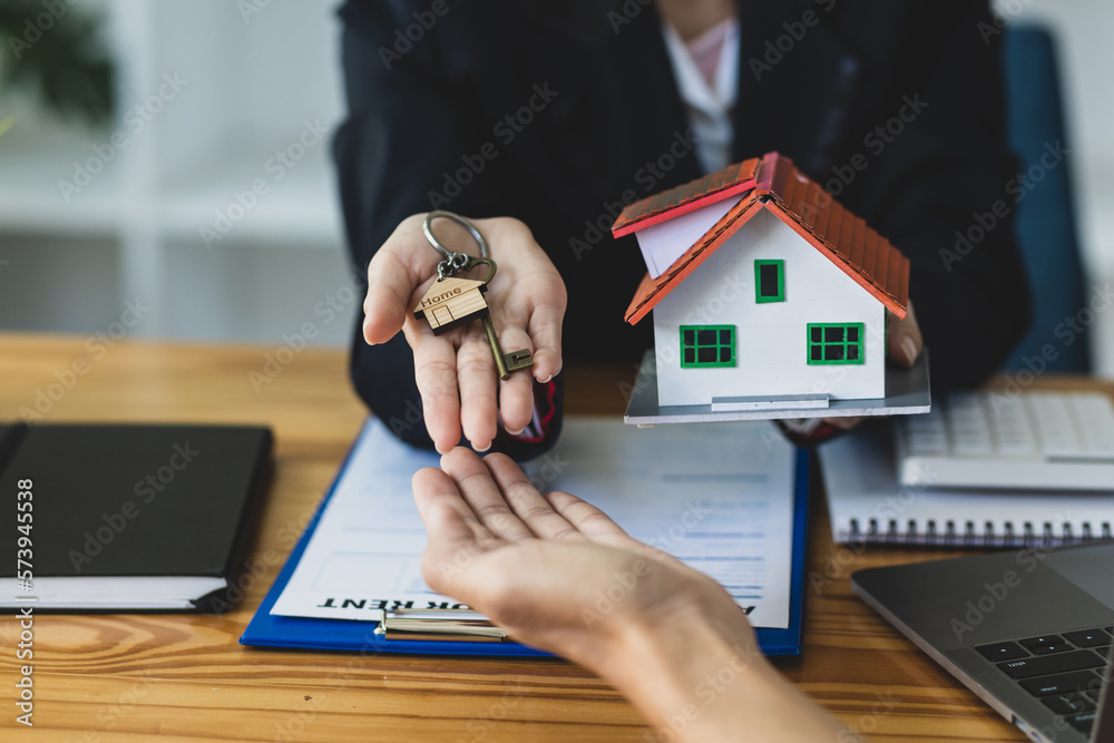 Real estate agent holding keys and model house showing to client, rental house concept.