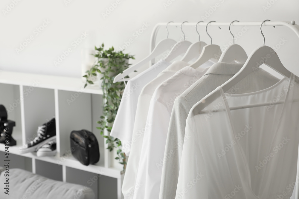 Rack with light clothes in makeup room, closeup