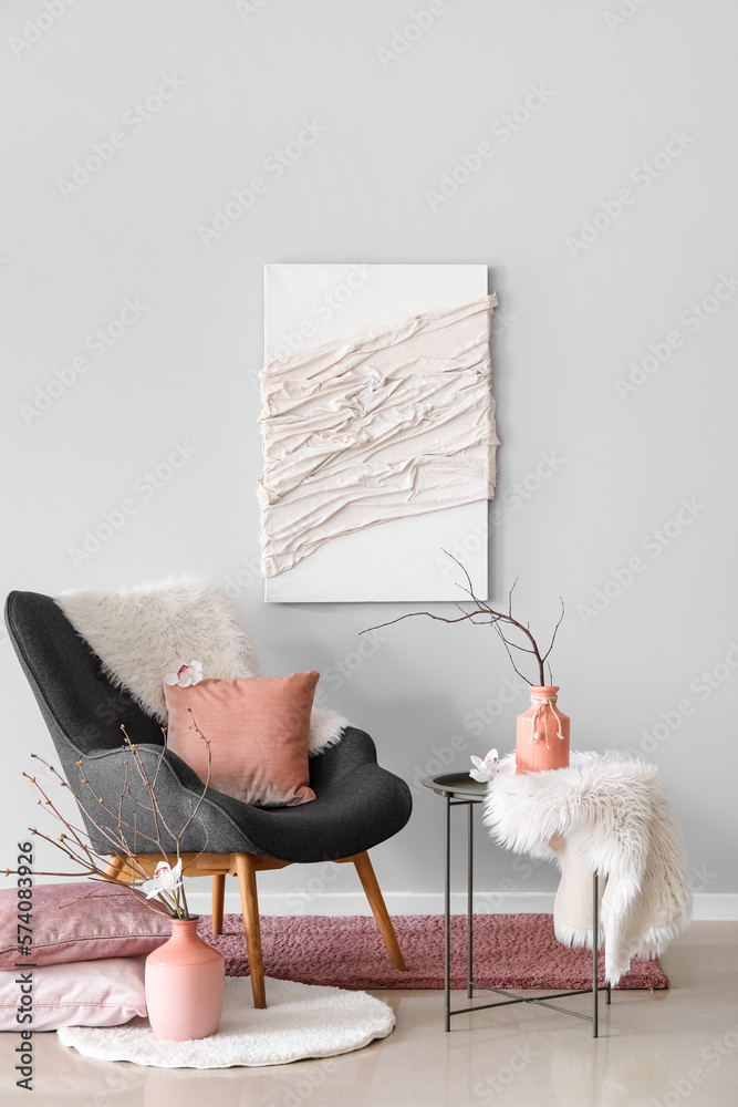 Interior of living room with armchair and tree branches in vases