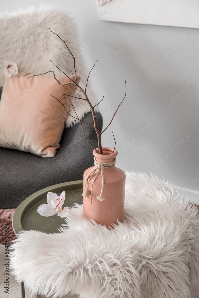 Vase with tree branch and flower on table in living room