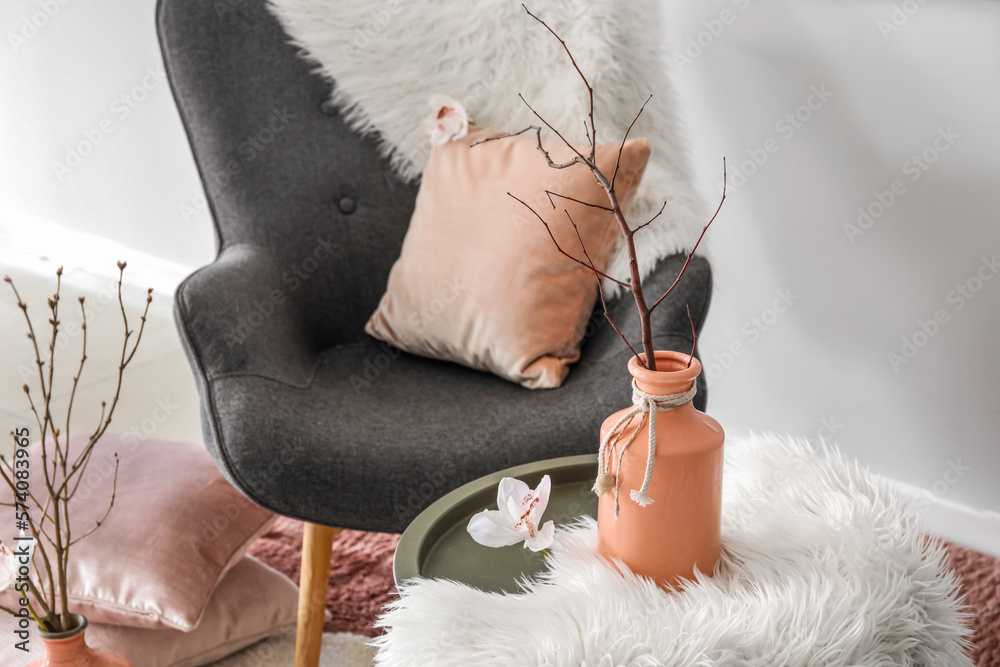 Vase with tree branch and flower on table in living room