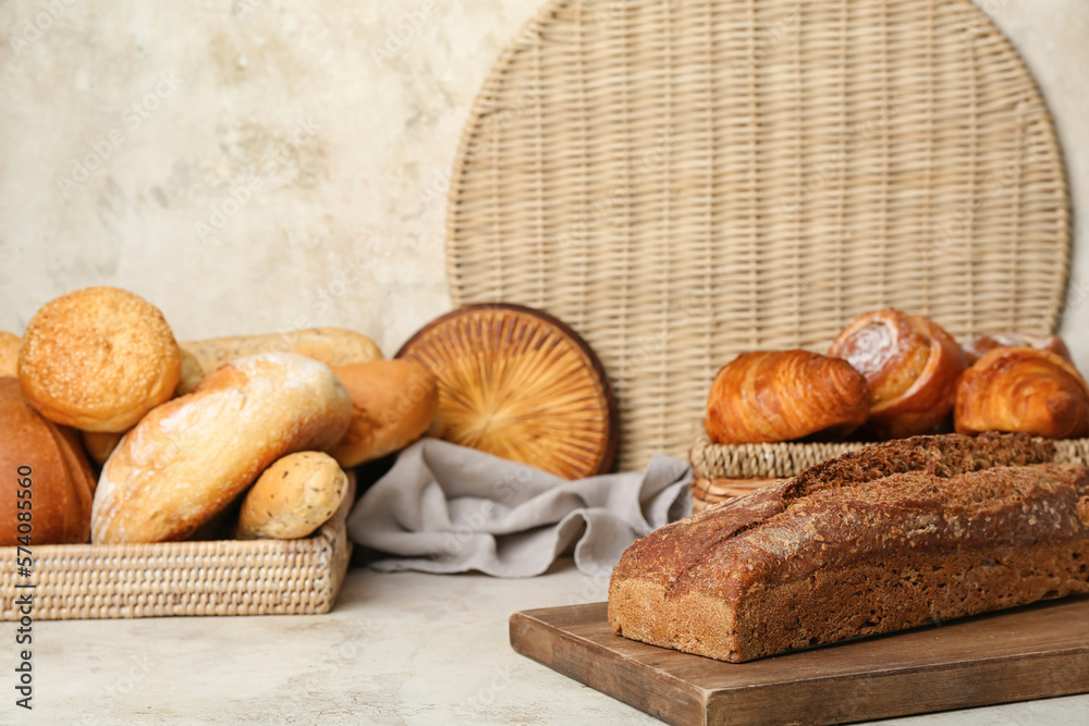 Loaves of different bread, croissants and cinnamon roll on white table