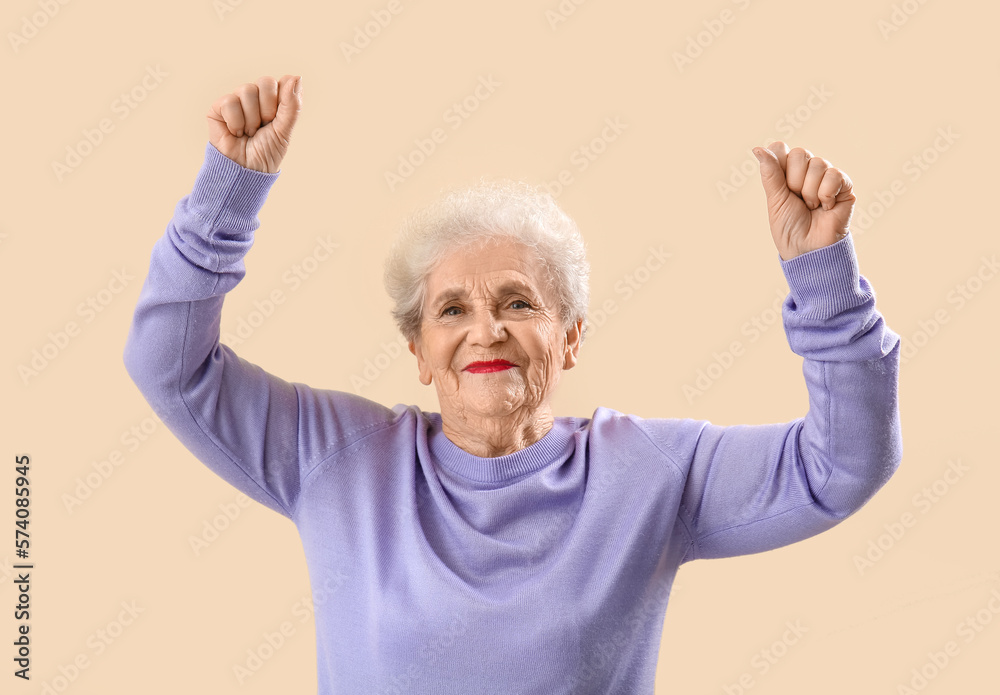 Senior woman in lilac sweater dancing on beige background