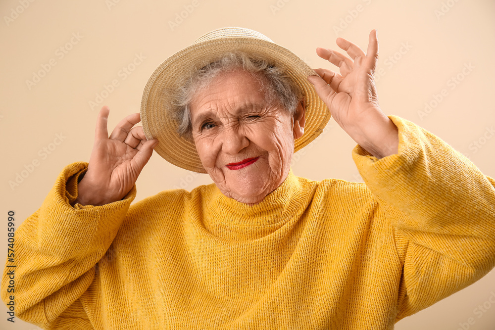 Senior woman in hat on beige background