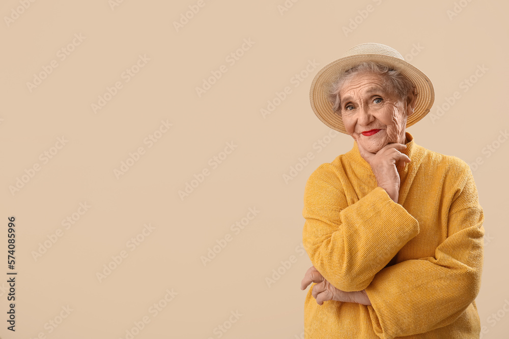 Thinking senior woman in hat on beige background