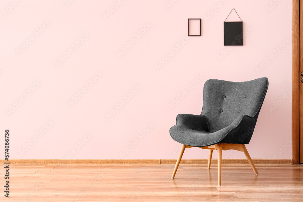 Stylish grey armchair near pink wall