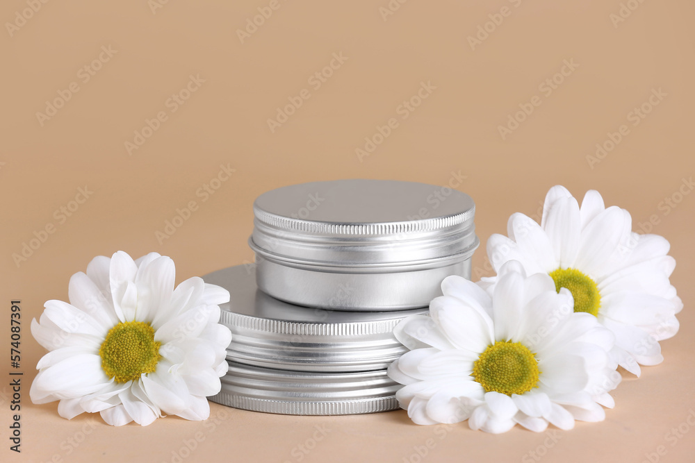 Jars of cosmetic products and chamomile flowers on color background