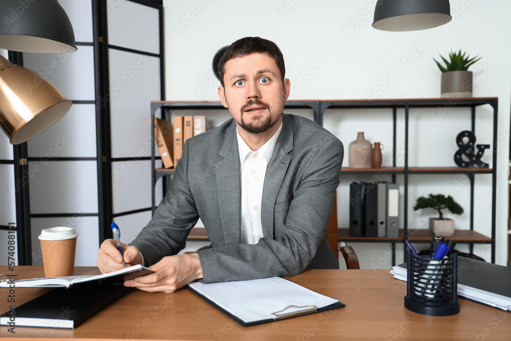 Male tutor writing in notebook while giving online lesson at home