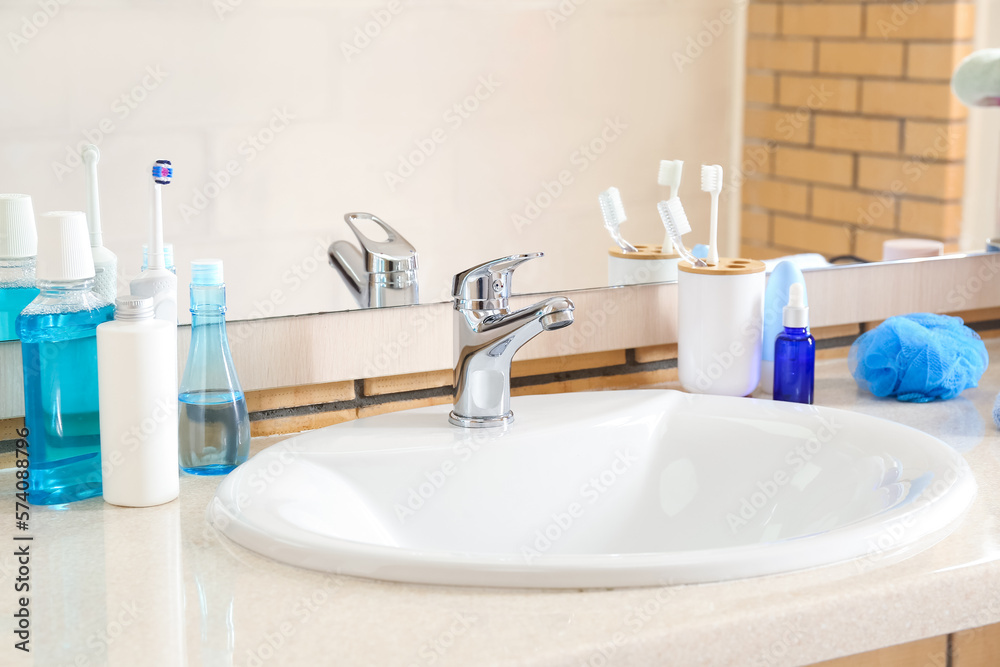 White ceramic sink and bath supplies on table near mirror