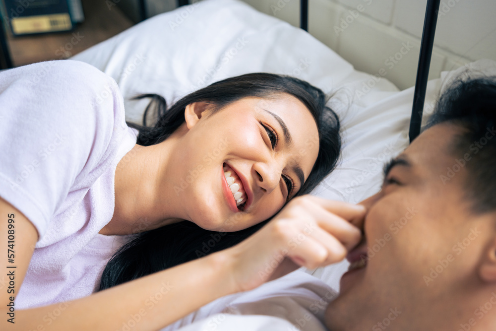 Asian new marriage couple lying down on bed and looking at each other. 