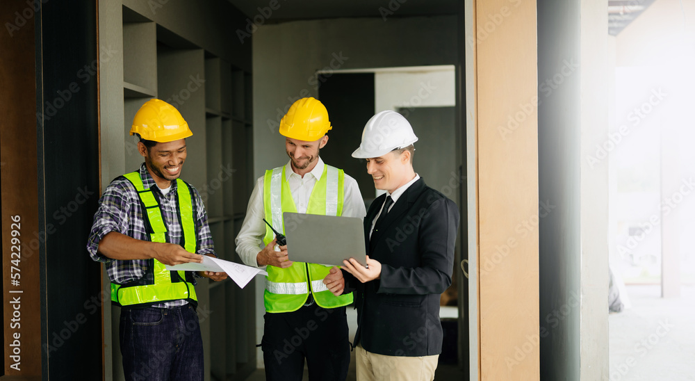 Contractor and architect looking at plan, tablet, laptop and talking about working on big project. B