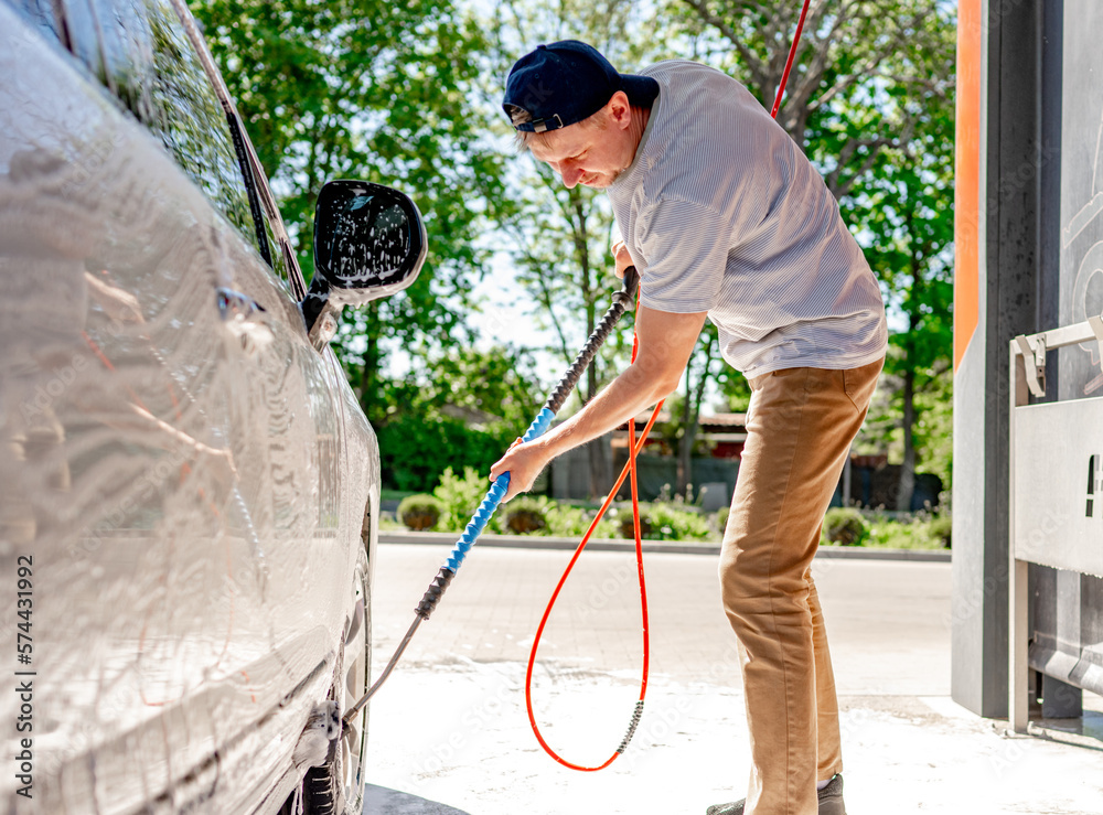 A man washing a car at a self-service car wash