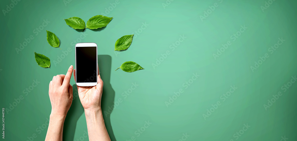 Person holding a smartphone with green leaves